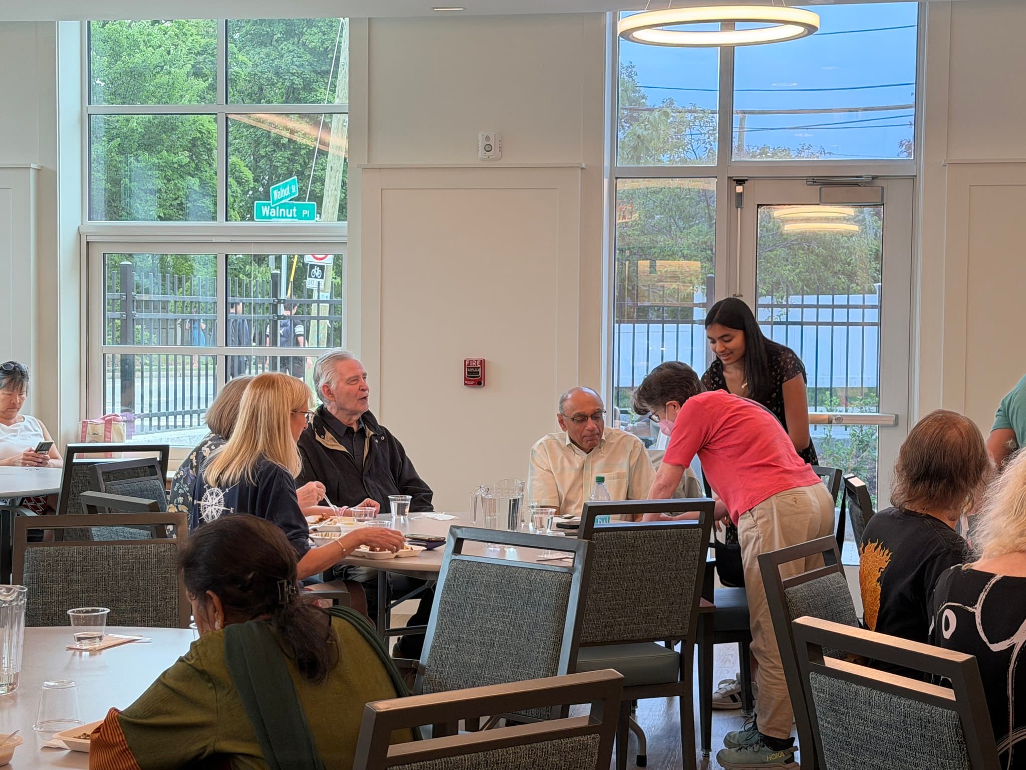 Naaisha leans in to help a senior explore AI during a workshop in Newton.